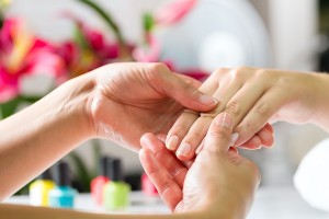 Woman in a nail salon receiving a manicure by a beautician, she is getting a hand massage